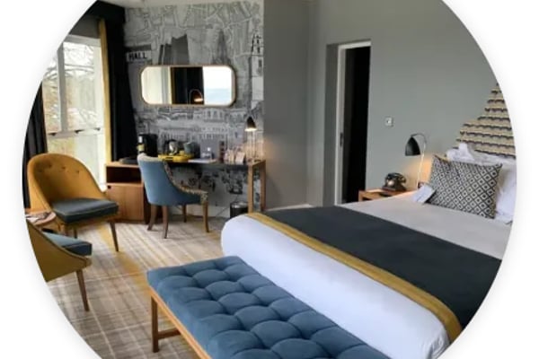 Modern bedroom with bed, blue bench, mustard chair, and desk area with gray accent wall