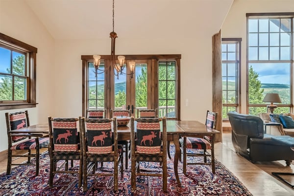Open-plan kitchen and dining area with wood cabinetry, black granite countertops, stainless steel appliances, and exposed wooden beams.